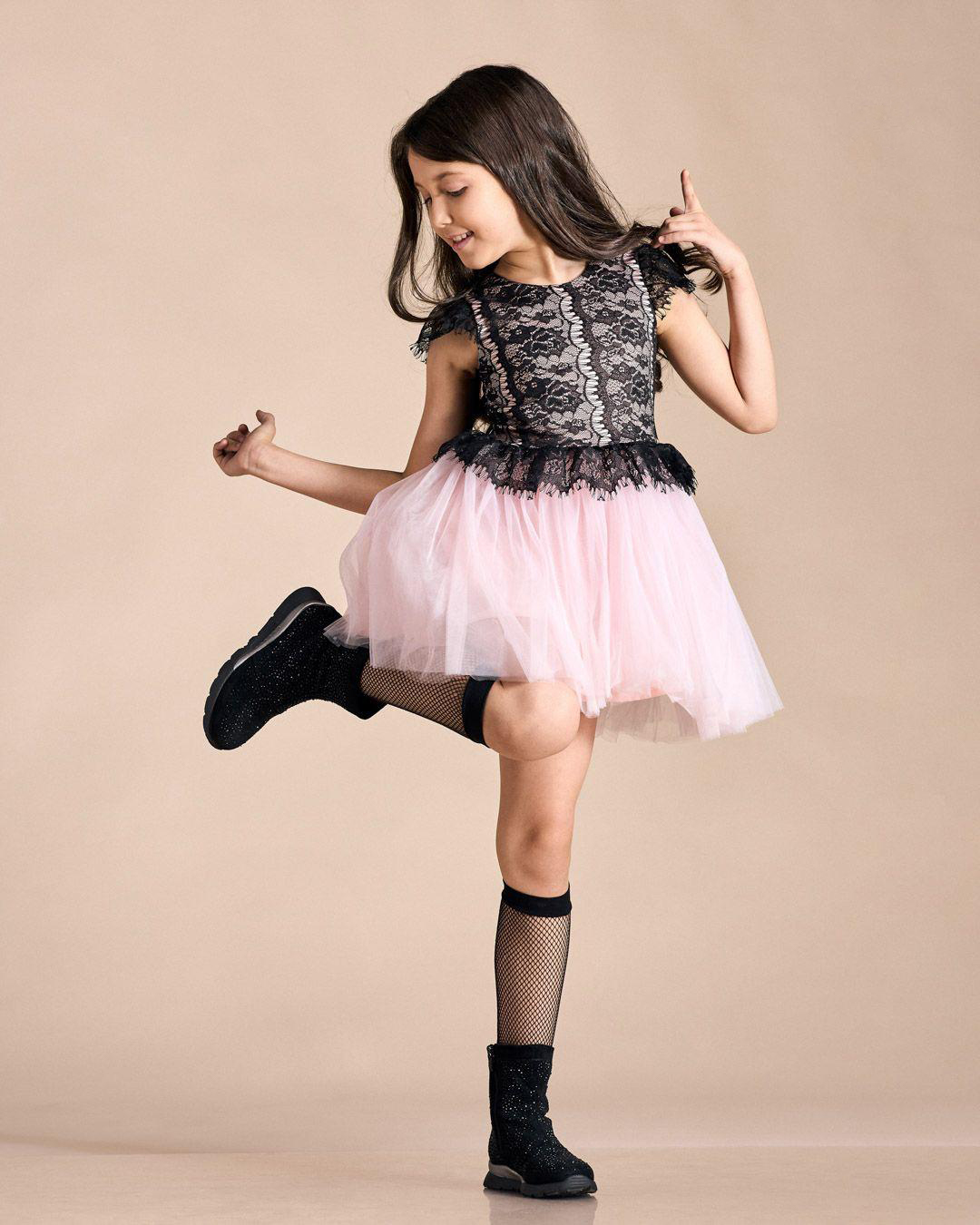 Little girl wearing a pink skirt and black t-shirt striking a pose