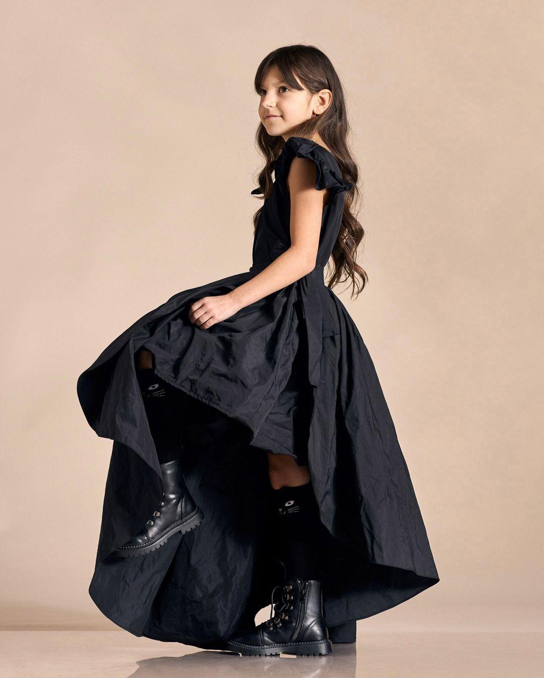 Little girl wearing a long black dress, striking a pose